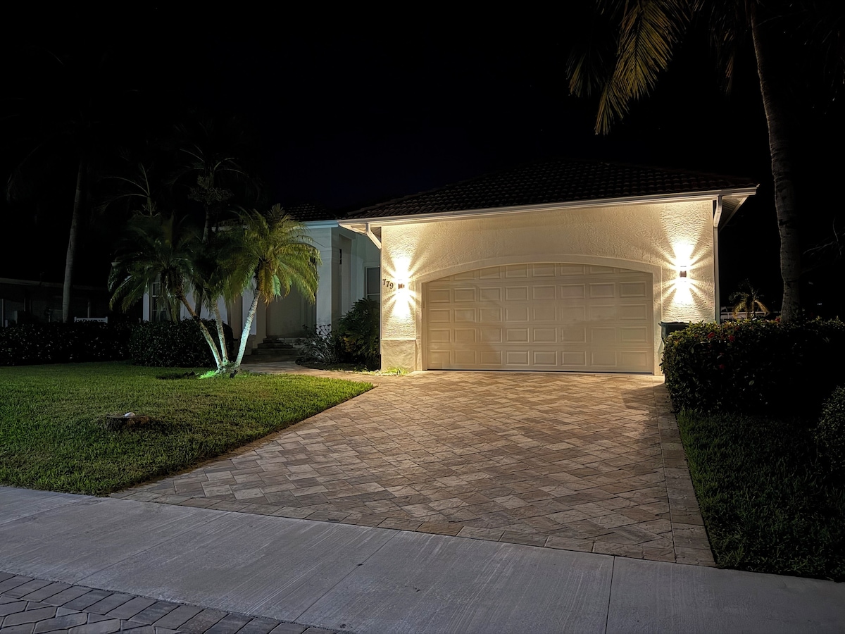 A house with a covered driveway, a garage, and a well-maintained lawn.