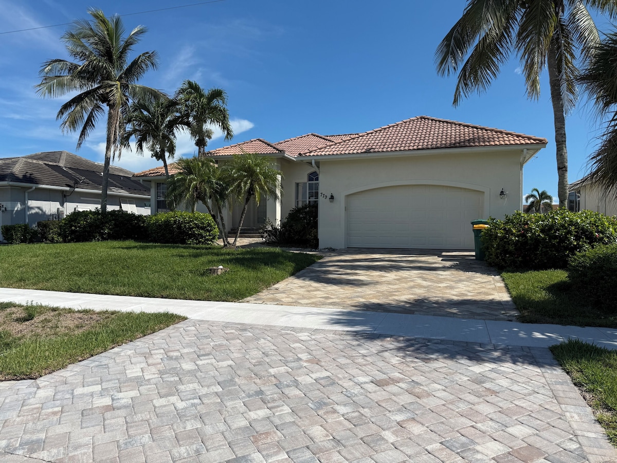 A residential house with a tiled roof, a driveway, and palm trees.