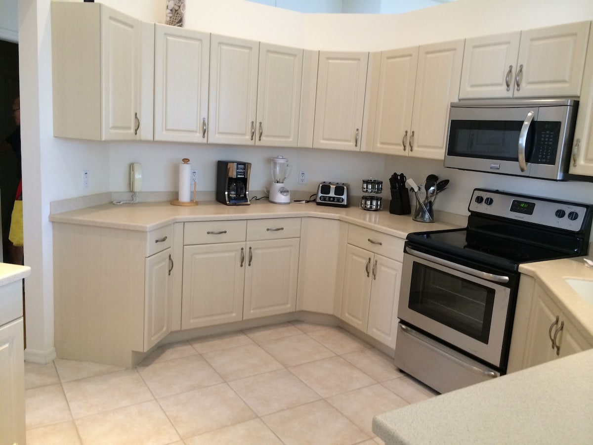 A modern kitchen with white cabinets, a microwave, a stove, and various appliances.