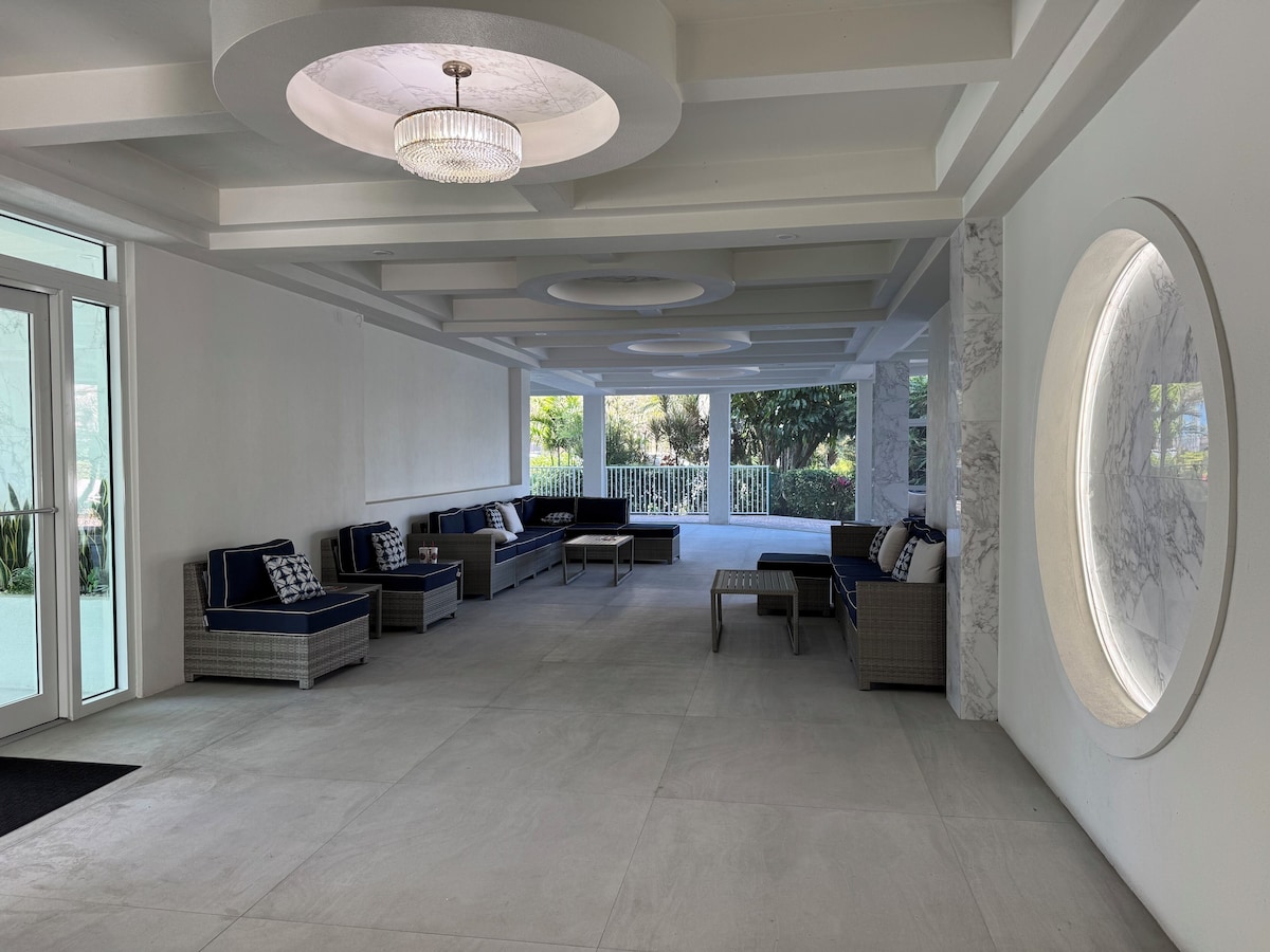 A spacious living area with a large sofa set, a coffee table, and a chandelier.