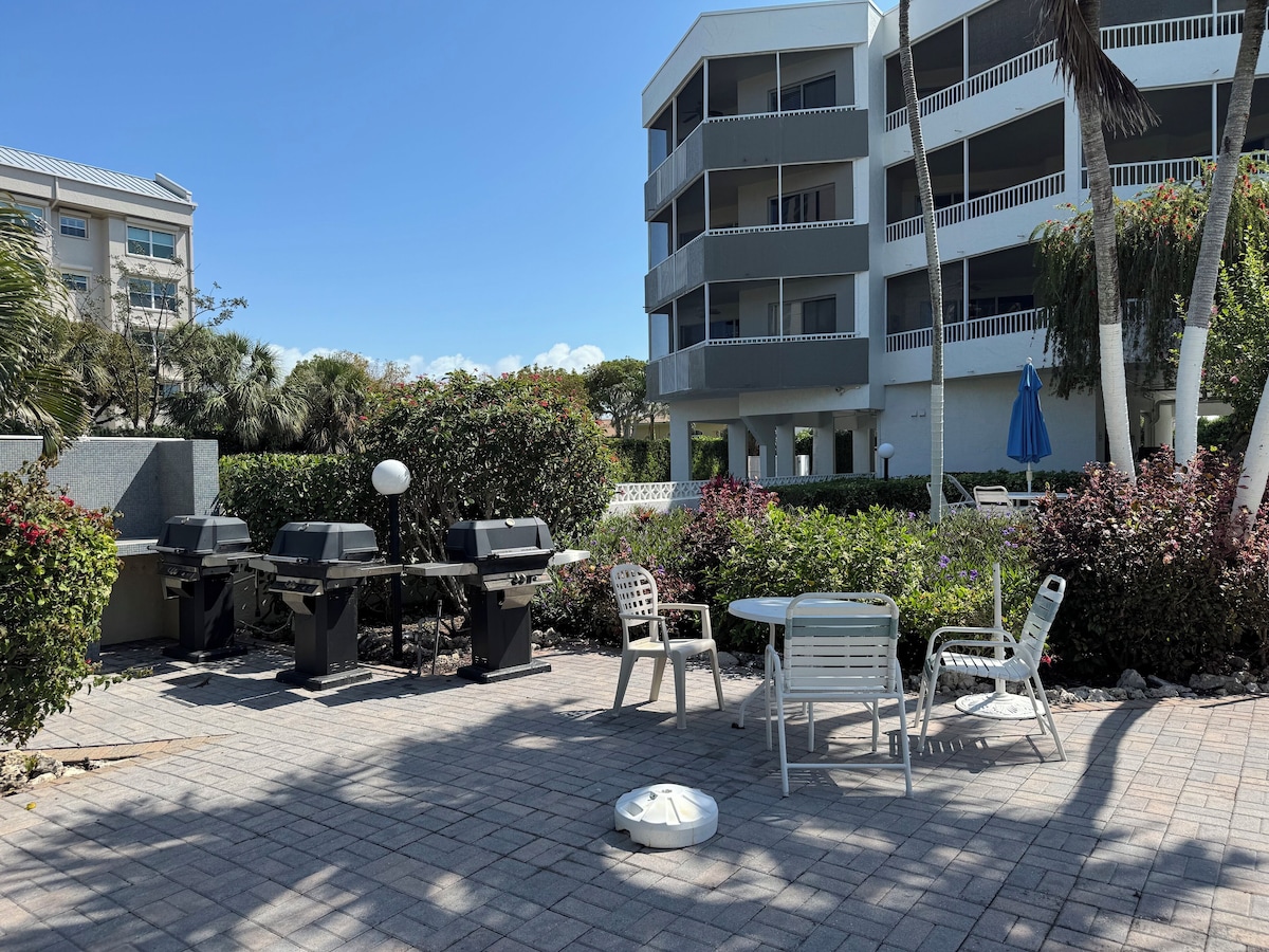 An outdoor patio area with barbecue grills, seating, and a white umbrella.