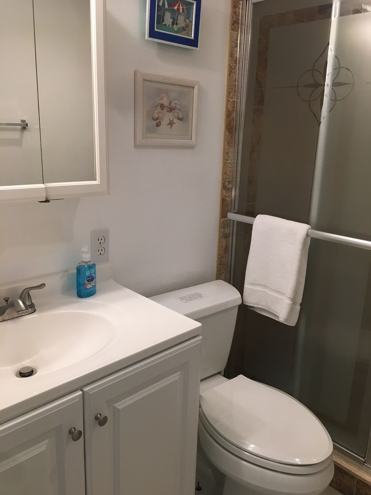 A bathroom with a white sink, a toilet, and a shower area.