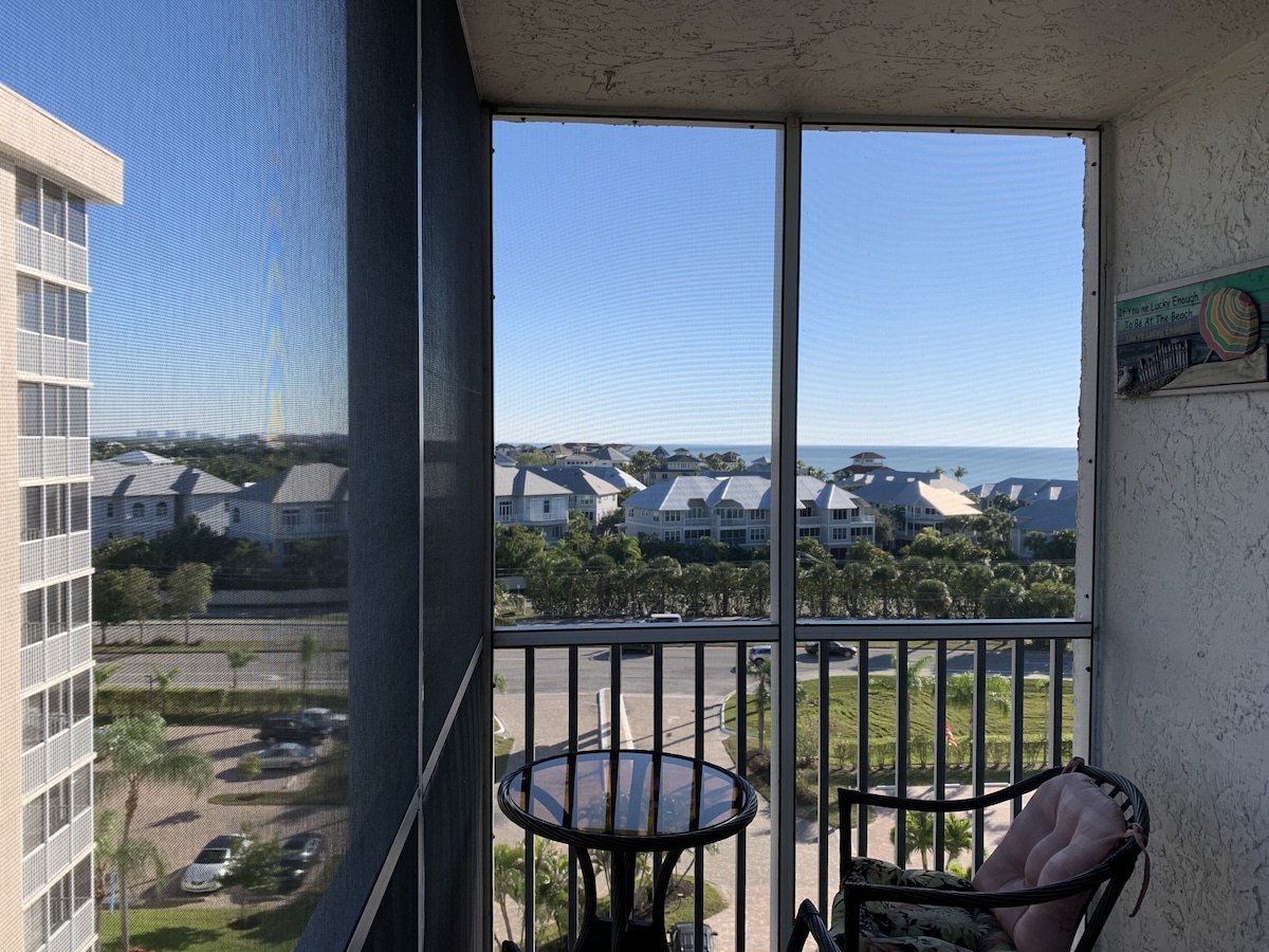 A balcony with a view of a residential area and the ocean.