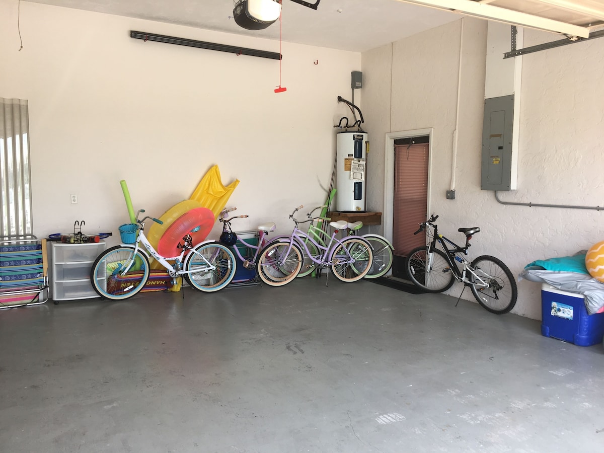 A garage with bicycles parked against the wall, a water heater, and a closed door.