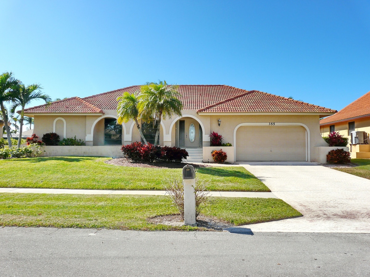 A residential house with a red-tiled roof, a front driveway, and a well-maintained lawn.