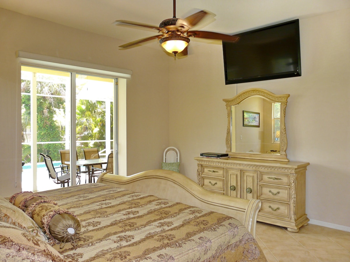 A bedroom with a bed, a dresser, a television, and a ceiling fan.