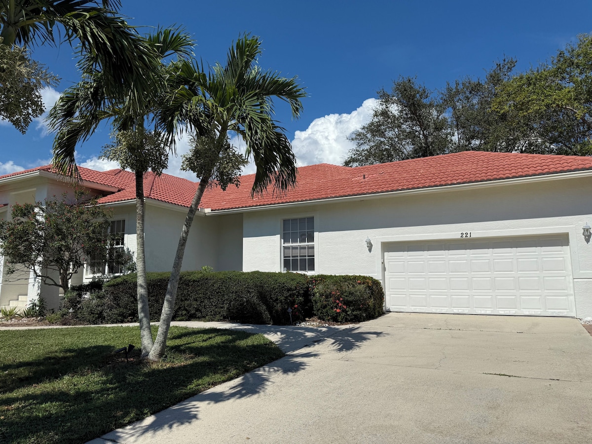 A single-story house with a red-tiled roof, a white garage door, and a well-maintained lawn.