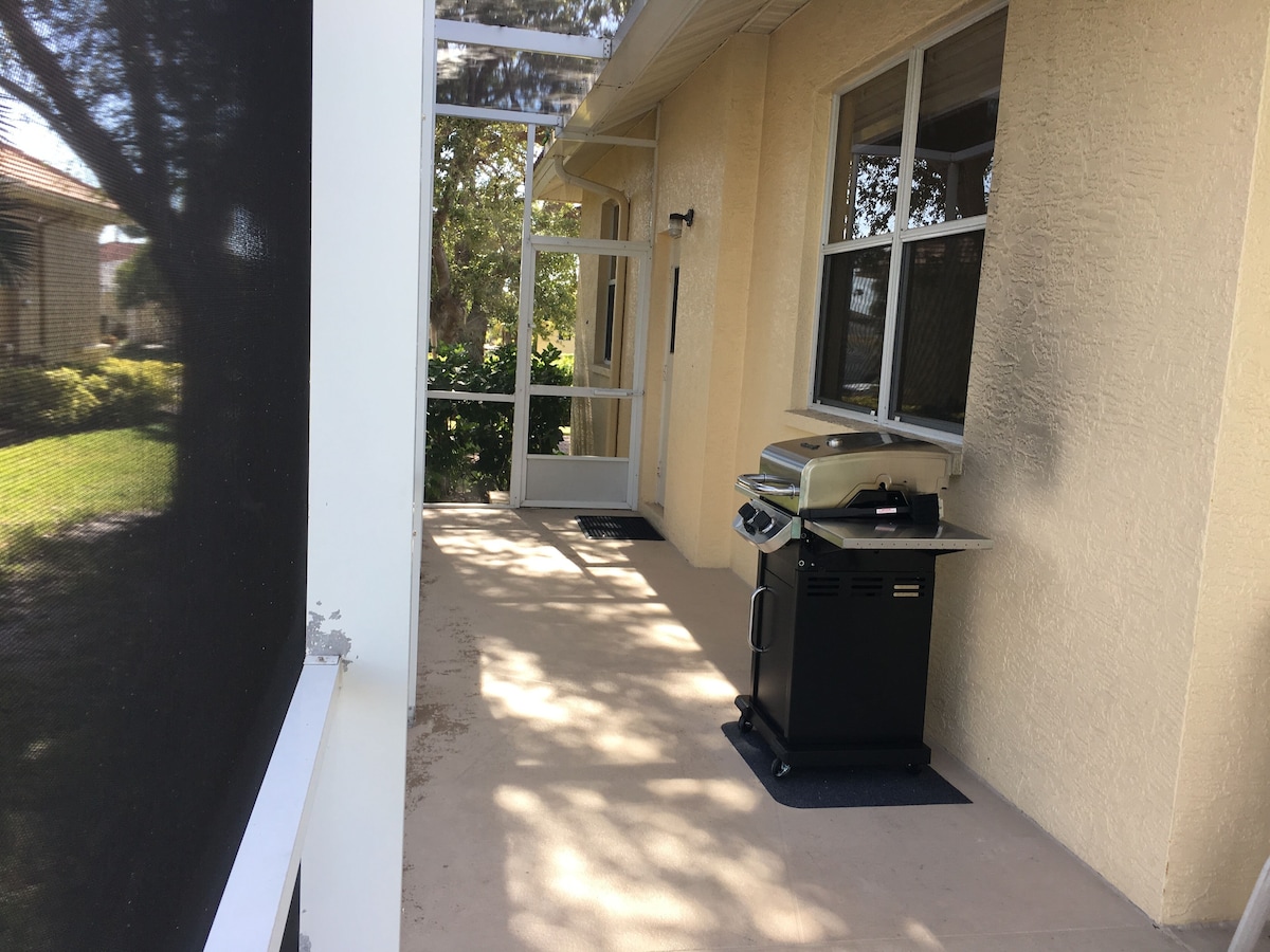 A covered outdoor area with a grill and a door leading to a garden.