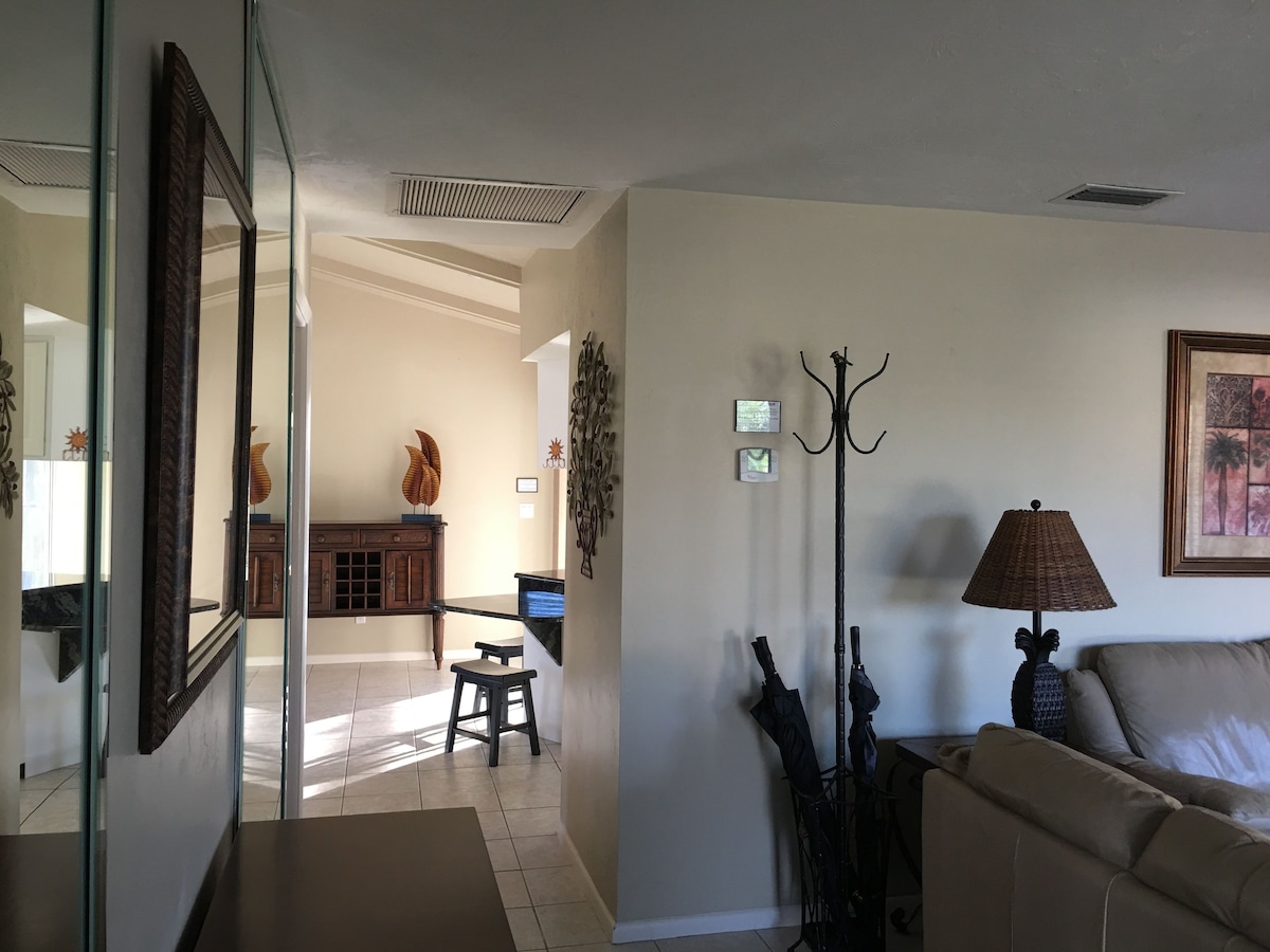 A living room with a sofa, a lamp, and a coat rack. There is a staircase leading to another room.