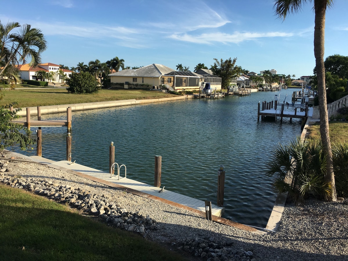 A waterfront property with a dock, a swimming pool, and a grassy area.