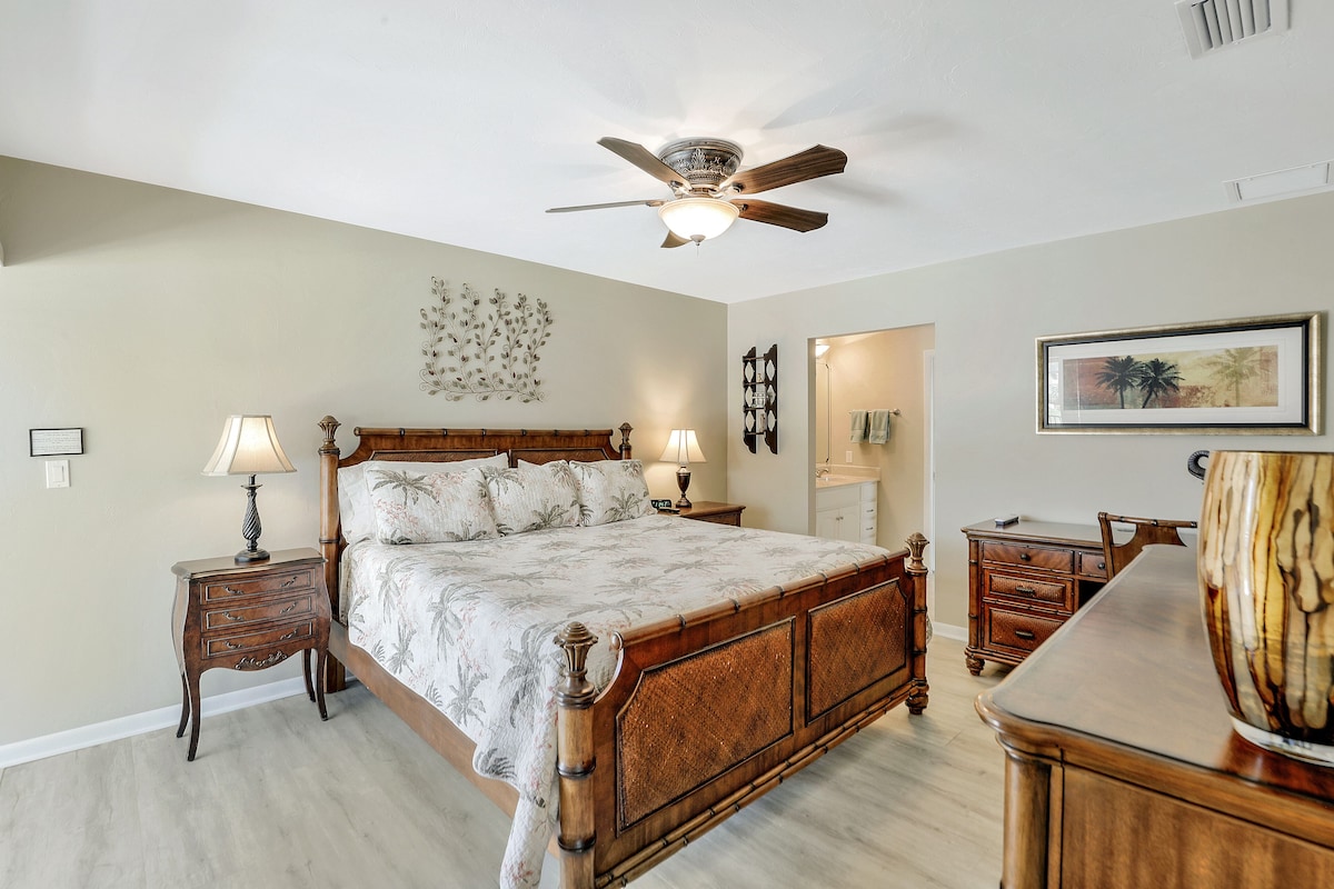 A bedroom with a wooden bed, two bedside tables, a ceiling fan, and a nightstand with a lamp.