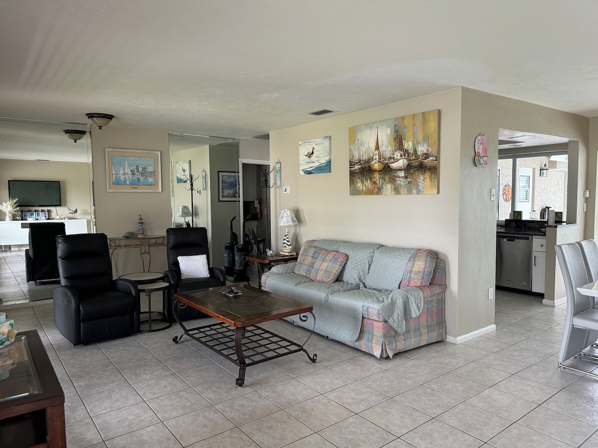 A living room with a sofa, chairs, a coffee table, and artwork on the walls.