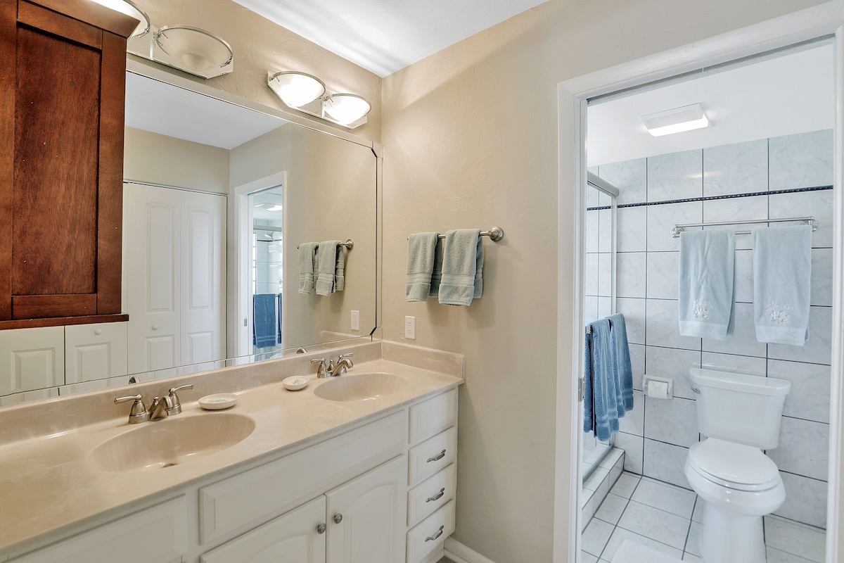A bathroom with two sinks, a mirror, and a shower.