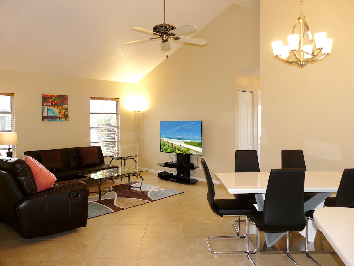 A living room with a sofa, TV, and dining area with chairs.