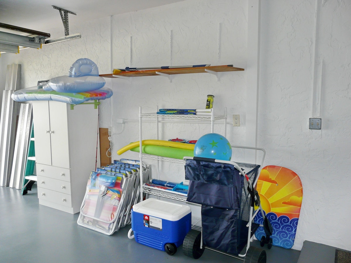 A room with a bunk bed, a desk, a chair, a shelf with sports equipment, and a storage unit.