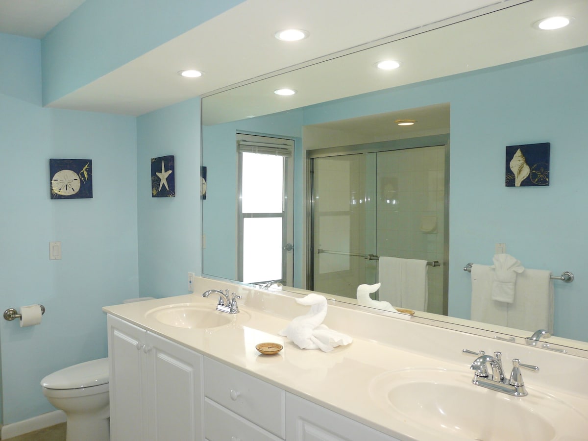 A bathroom with two sinks, a toilet, and a large mirror.