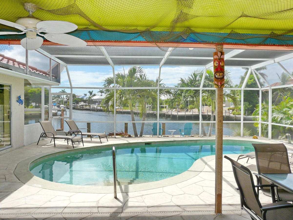 An indoor swimming pool with clear views of a marina and palm trees.